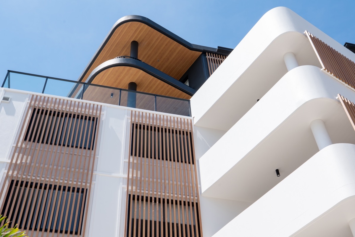 KOKOMO completed project showing curved balconies, a white façade and vertical timber-toned screens.